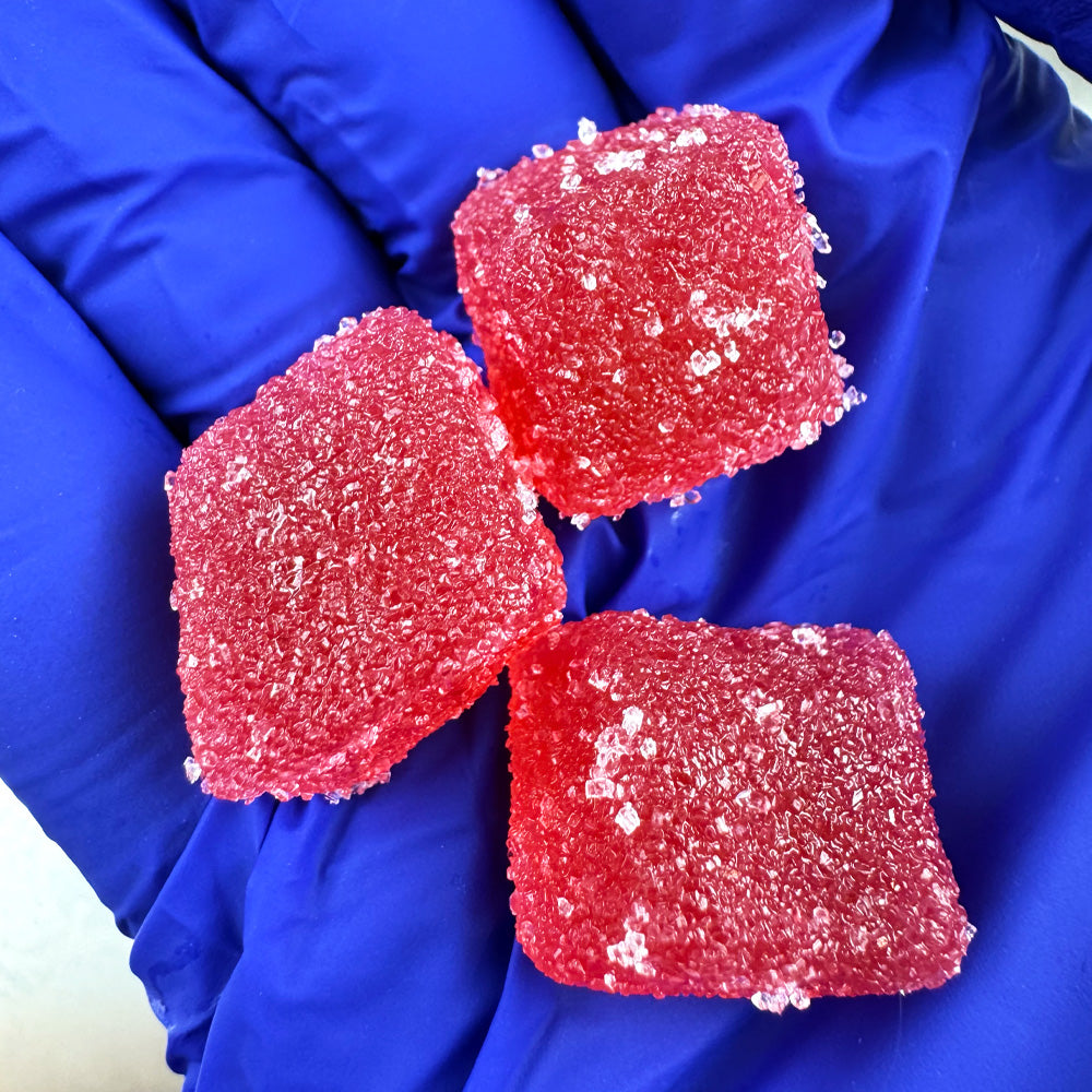 Main qui tient plusieurs gummies au THC rouges