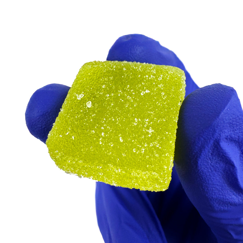 Gummies au THC verts goûts fraise tenu dans une main