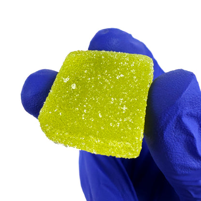 Gummies au THC verts goûts fraise tenu dans une main